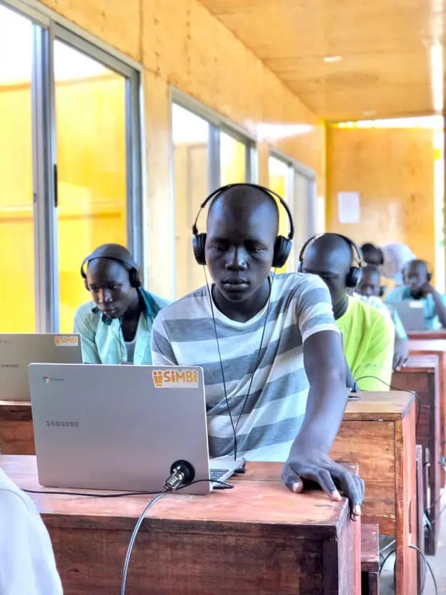 Students on laptops inside a BrightBox classroom in Bidibidi